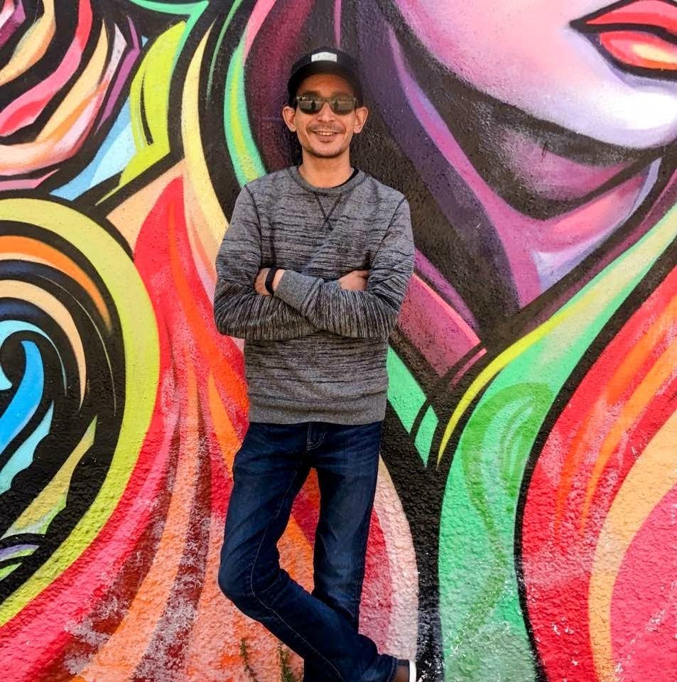 person posing against wall with mural art